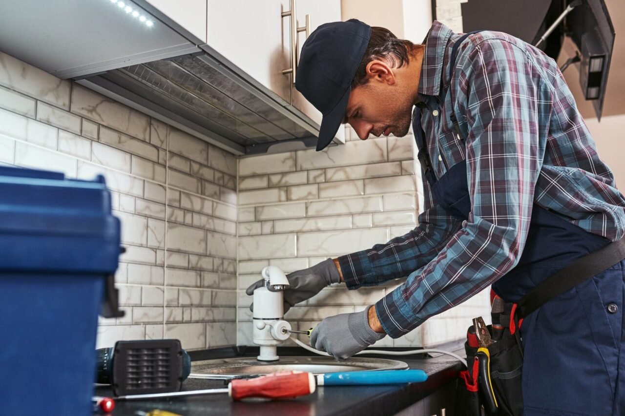 Licensed plumber repairing a leaking faucet in a Las Vegas kitchen